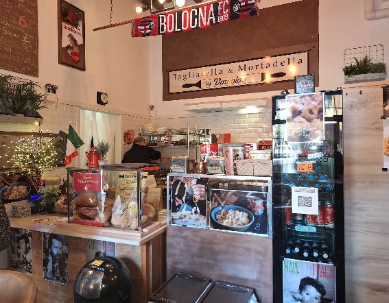 Bancone con insegna T&M e frigo espositore, luci natalizie — cuore operativo di Tagliatella e Mortadella Bologna