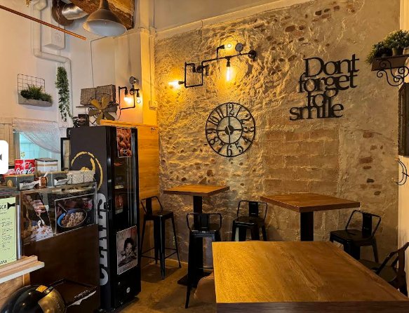 Muro in pietra viva con scritta Don't forget to smile, orologio vintage e luci calde industriali — atmosfera ristorante Bologna