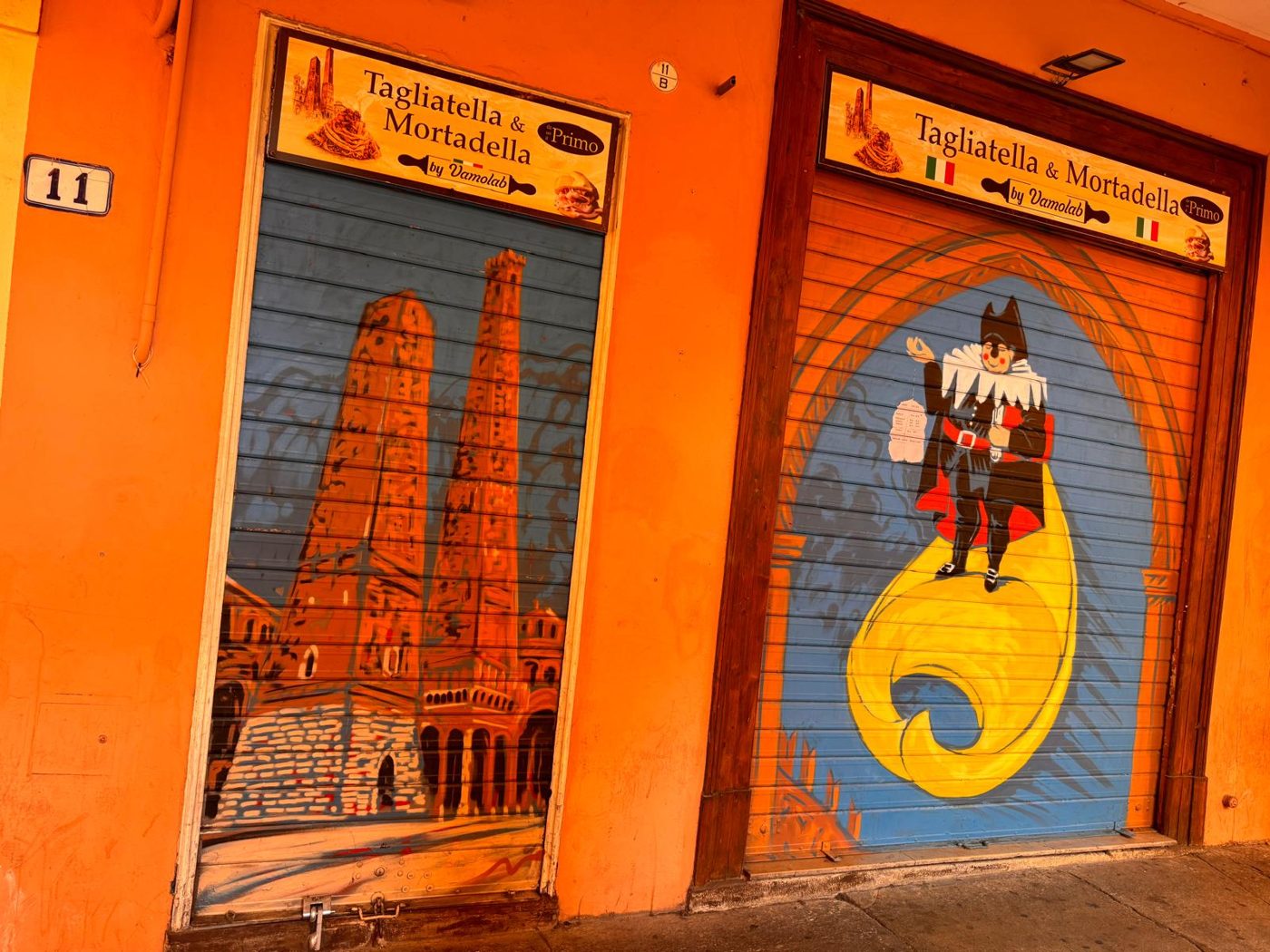 L'ingresso di Tagliatella & Mortadella in Via Petroni 11 A/B, Bologna, con le serrande dipinte